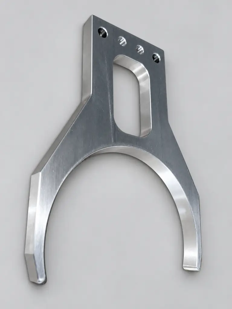 A machined metal component with a fork-shaped profile, shown complete