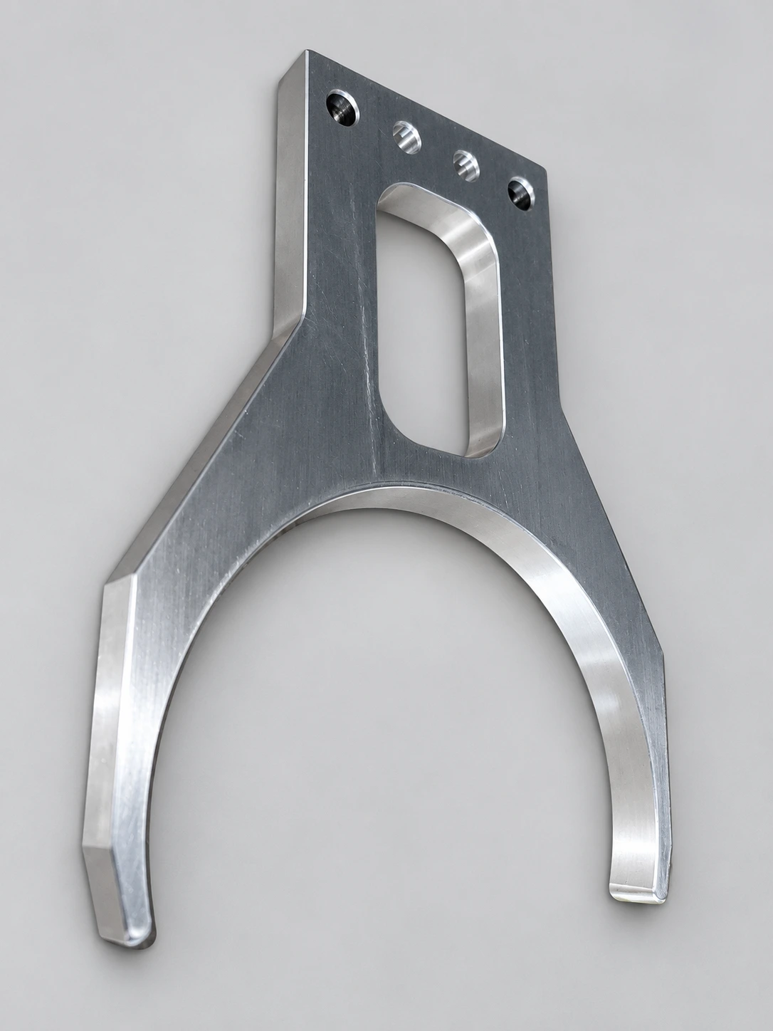 A machined metal component with a fork-shaped profile, shown complete